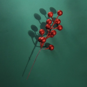 Close-up of red glitter artificial berries for Christmas decoration on a dark green background