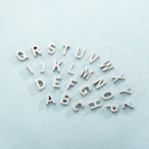 Macro view of 26 silver stainless steel letter charms for DIY necklace making