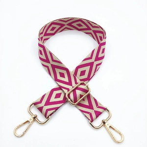 Detail of colorful geometric embroidery on a wide shoulder strap with golden metal clips