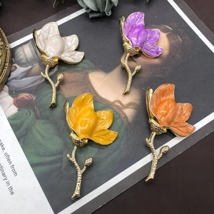 Detail of colorful enamel magnolia brooches in four colors on a vintage floral background