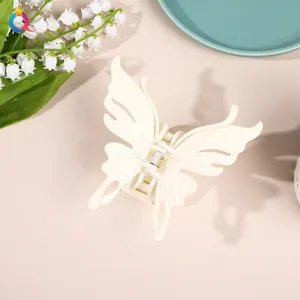 Close-up of a large cream butterfly hair claw clip next to lily of the valley flowers