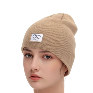 Detail of khaki knitted beanie featuring a white fabric patch with infinity symbol and text
