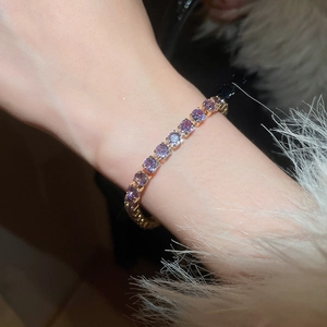 Detail of tennis bracelet with purple zircons and gold base worn on a soft furry cuff