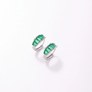 Gros plan de boucles d'oreilles huggies argentées avec zircons vert émeraude