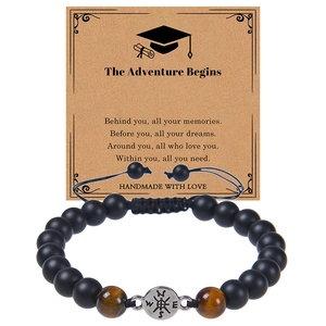 Detail of tiger eye beads and metal compass charm on a black woven adjustable bracelet