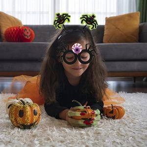 Girl wearing Halloween spider headband, funny glasses and zombie gloves set for party fun