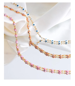 Macro view of colorful enamel evil eye necklaces reflecting on a mirror over white silk