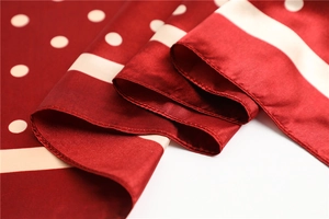 Macro detail of red satin scarf with beige polka dots and fine stitched edges