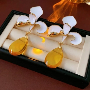 Vintage Orchideenohrringe mit weißem Emaille und gelben Anhängern in einer Schmuckschatulle