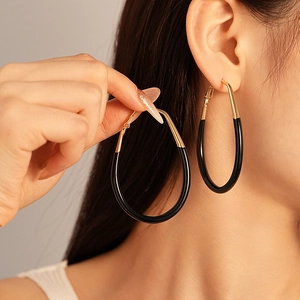 Exaggerated retro teardrop earrings in black and gold finish on a female model