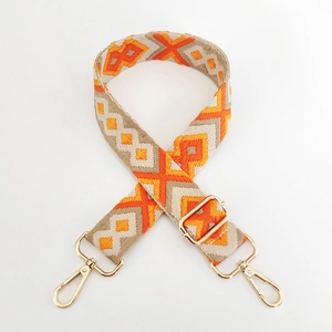 Close-up of geometric embroidered bag strap with golden metal spring hooks and adjusters
