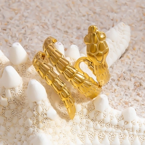 Minimalist gold snake wrap ring displayed on a starfish with a beach sand background