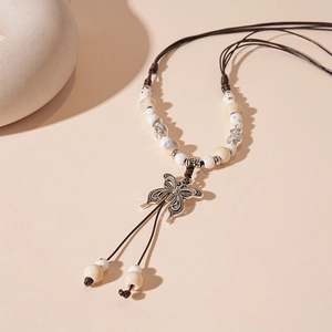 Close-up of retro hollow butterfly pendant with ceramic beads on a braided rope necklace
