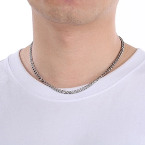 Close-up of a silver Cuban link chain necklace worn by a model on a white shirt