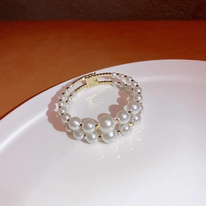 Detail of double-layer pearl bracelet with rhinestones and gold plating on white plate