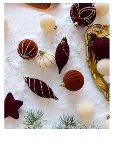 Flat lay of velvet Christmas ornaments in wine red and cream with gold glitter details