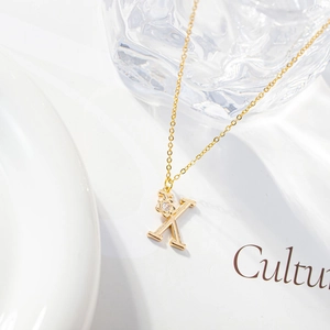 Macro view of gold letter K necklace pendant with micro-inset zircon and shiny finish