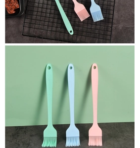Detailed view of silicone pastry brushes in mint green, light blue, and pink on a grill