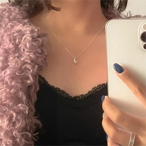 Close-up of minimalist sterling silver necklace with zircon heart pendant worn by model
