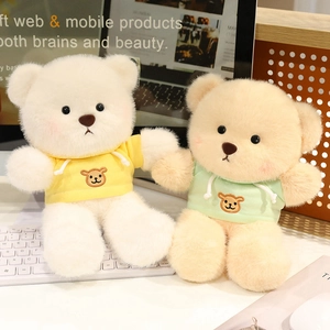 Cute teddy bear plush toys in yellow and green hoodies on a cozy desk setting