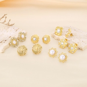 Detailed view of gold plated stud earrings with pearls and rhinestones on stone decor