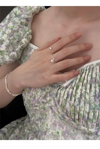 Macro shot of 925 sterling silver pearl rings and multi-layer bead bracelet on a floral dress