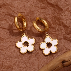 Close-up of vintage golden hoop earrings with white hollow flower pendants and pearly finish