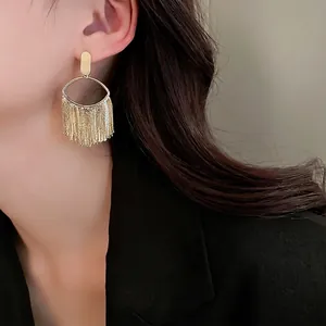 Gold plated oval stud earrings with long metal tassels shown on a female model