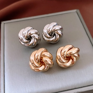 Macro view of gold and silver knot-shaped metal earrings on jewelry tray