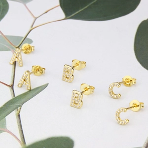 Macro detail of gold-plated alphabet earrings A B C with shimmering cubic zirconia