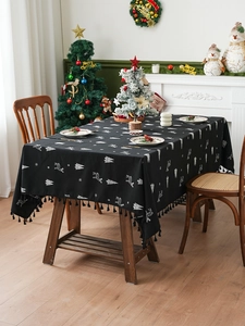 Detail of black linen tablecloth with white reindeer and tree patterns and fringe