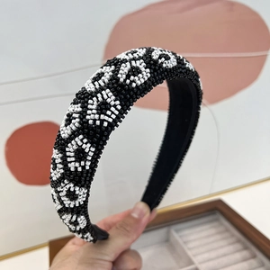 Detail of hand-sewn beadwork on a black and white geometric pattern wide headband