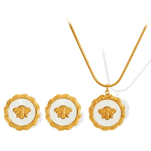 Set collana e orecchini ape dorata con ciondolo a conchiglia bianca su fondo neutro