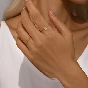 Detail of adjustable gold chain rings with star and zircon flower charms worn on finger