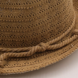 Close-up of brown raffia sun hat showing breathable hollow weave and decorative rope