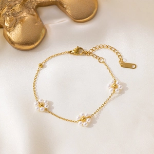 Elegant gold pearl flower bracelet with three floral motifs on white silk background