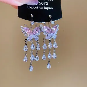 Detail of butterfly drop earrings with pink zircon stones and long tassel fringe