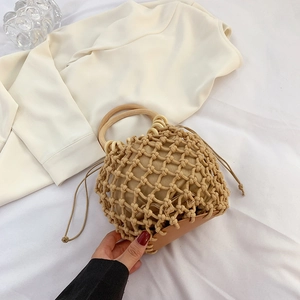 Detail of handmade straw bag with round wooden handles and beige drawstring inner pouch