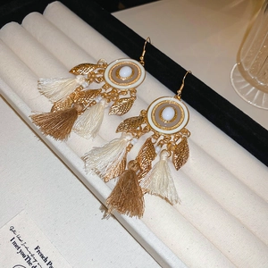 Detail showing Bohemian tassel earrings with gold leaf charms and beaded textures