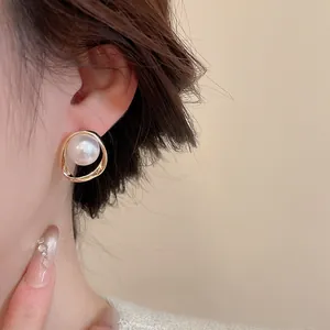 Close-up of elegant 18K gold floral pearl stud earring worn on a model's ear