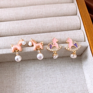 Dettaglio di orecchini a forma di pony in smalto con perle e cristalli su vassoio