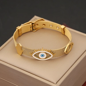 Detailed close-up of golden mesh evil eye bracelet with hamsa hand charm on jewelry box