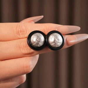 Macro shot of silver textured moon-surface stud earrings with minimalist black circular borders