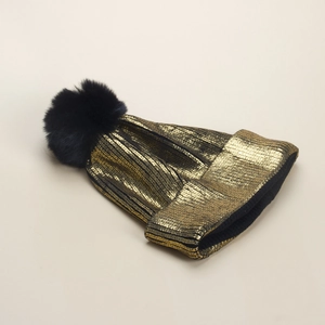 Berretto in maglia metallizzata dorata da donna con pompon nero in ecopelliccia