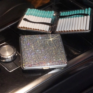 Detailed view of rhinestone cigarette case interior with cigarettes on dark car console