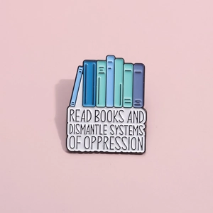 Detail of enamel book brooch featuring Read Books and Dismantle Systems text