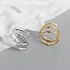 Close-up of gold and silver twig-textured adjustable rings on crumpled paper