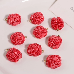 Close-up of nine red resin brain charms with golden loops on a clean white plate