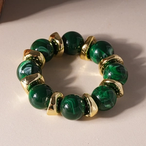 Detailed shot of dark green marbled acrylic beads and gold metallic spacers on a bracelet