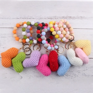 Colorful silicone bead wristlet keychain with knitted heart charm on a wood background